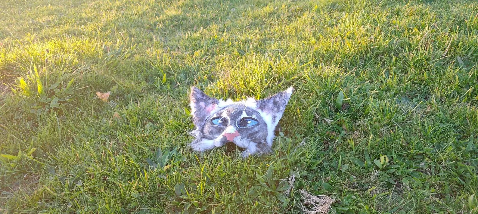 Grey and white tabby therian mask, front view in grass
